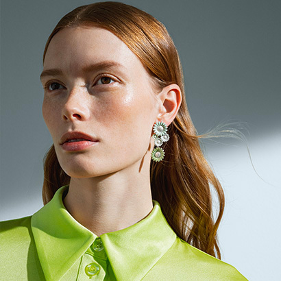 long earrings in Rhodium plated sterling silver, white enamel from the Daisy collection on model with green shirt in collaboration with Danish designer Stine Goya x Georg Jensen