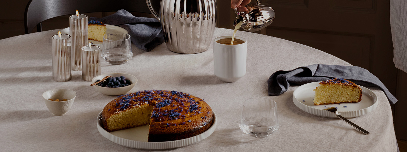 White porcelain plates and coffee mug and mirror polished stainless steel cutlery, pitcher and milk jug from the Bernadotte collection inspired by Sigvard Bernadotte