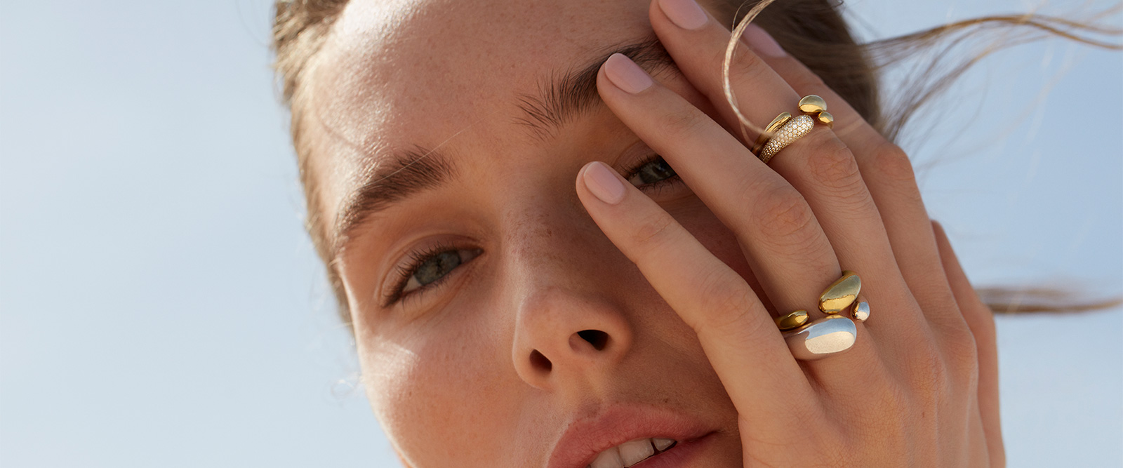 On model photo of Georg Jensen Mercy collection rings in 18kt yellow gold with diamonds and sterling silver