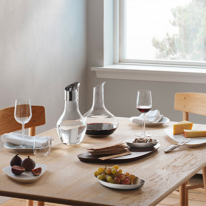 apperitivo set up on a dining table featuring carafe, pitcher and wineglass in glass and serving boards in marble from the Sky collection designed by Aurelian Barbry for Georg Jensen