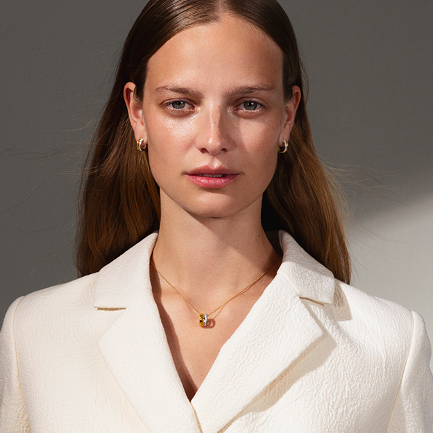 small earhoops and pendant in 18-karat yellow gold with diamonds on model with blazer from the Fusion collection created by Nina Koppel for Georg Jensen