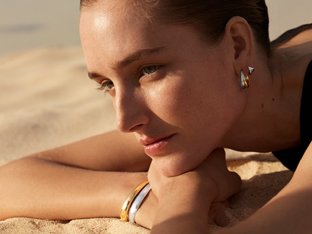 Georg Jensen on model photo of Curve collection sterling silver bangle and earrings in 18kt. Yellow gold and sterling silver