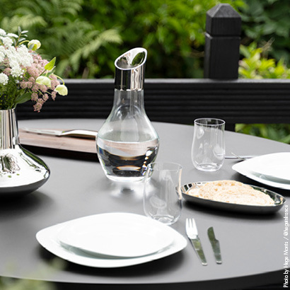 Outdoor tablesetting featuring mirror polished stainless steel and porcelain vase and porcelain plates
