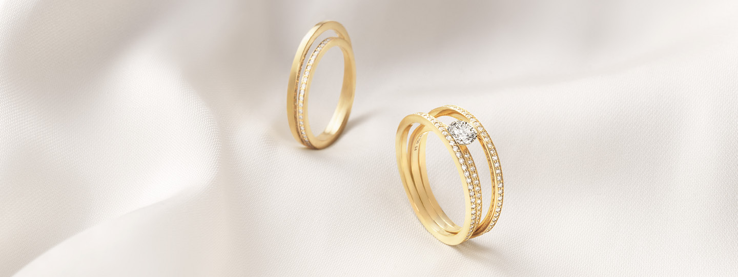 Halo solitaire ring and eternity ring from Georg Jensen in 18 karat gold and diamonfds