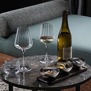 Crystal clear wine glasses and oak serving tray with mirror polished stainless steel bowls from the Bernadotte collection inspired by Sigvard Bernadotte