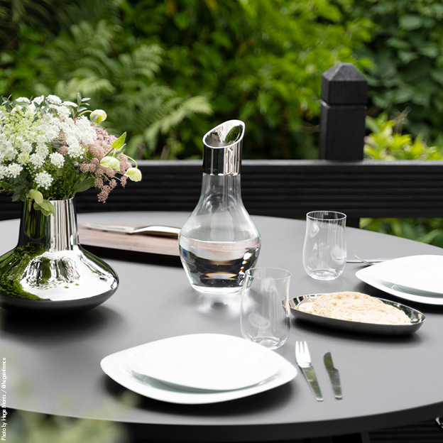 Sky and Cobra table setting items from Georg Jensen displayed on a garden table