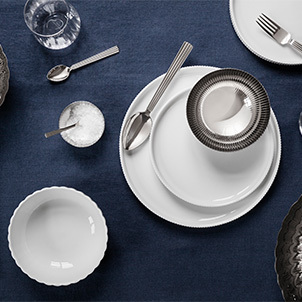 White porcelain plates and bowls and mirror polished stainless steel cutlery and bowl from the Bernadotte collection inspired by Sigvard Bernadotte