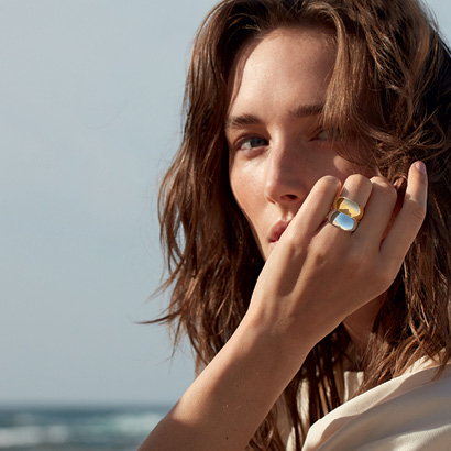 Georg Jensen Curve collection yellow gold and sterling silver rings on model with nature background