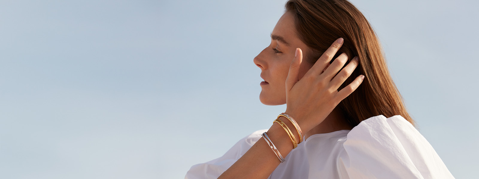 On model image of the Fusion collection bangles in 18 kt. gold and sterling silver designed by Nina Koppel