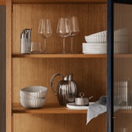 Crystal clear wine classes, porcelain plates and bowls and mirror polished stainless steel carafe from the Bernadotte collection