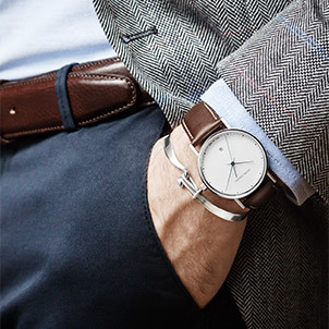 On model photo of Georg Jensen Koppel collection quartz Swiss made watch with brown calfskin strap and mens Torun bangle