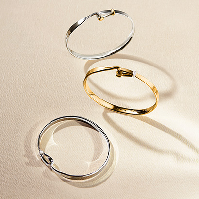 three bangles in Sterling Silver with18 kt. yellow gold and white diamonds on beige background from the Torun collection by Georg Jensen jewellery