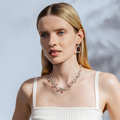 earrings and neckting in Sterling Silver on model wearing a white top from the Offspring collection designed by Jacqueline Rabun for Georg Jensen