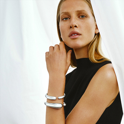bold jewellery bangles in Sterling Silver on model with black top in a white background wearing mercy pieces by georg jensen