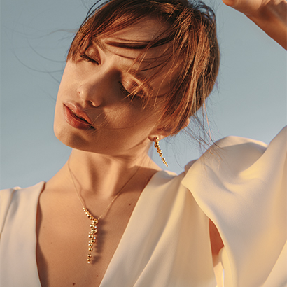 18 kt. gold grapes inspired necklace with pendant and earrings on model from the Moonlight Grapes collection designed by Georg Jensen