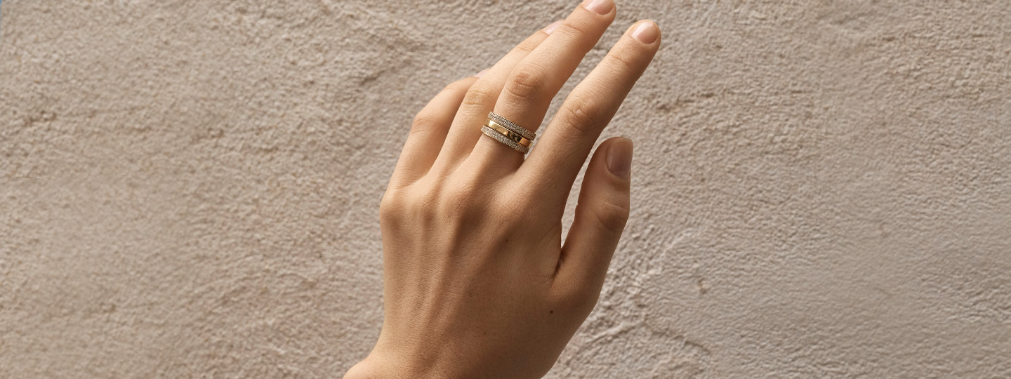 ring in yellow gold with diamonds from the magic collection by georg jensen on hand with beige background