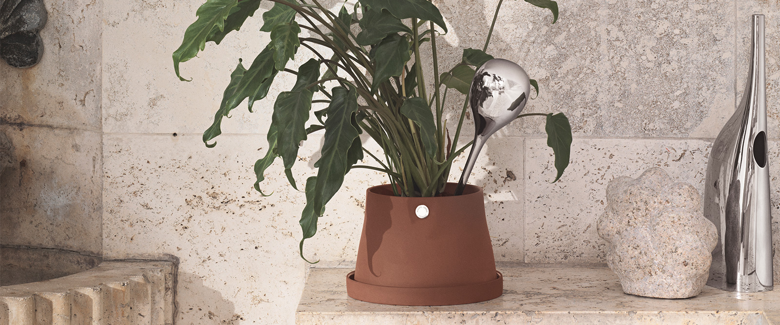Big terracotta pot, water globe and mirror polished stainless steel water can from the Terra collection designed by Snøhetta